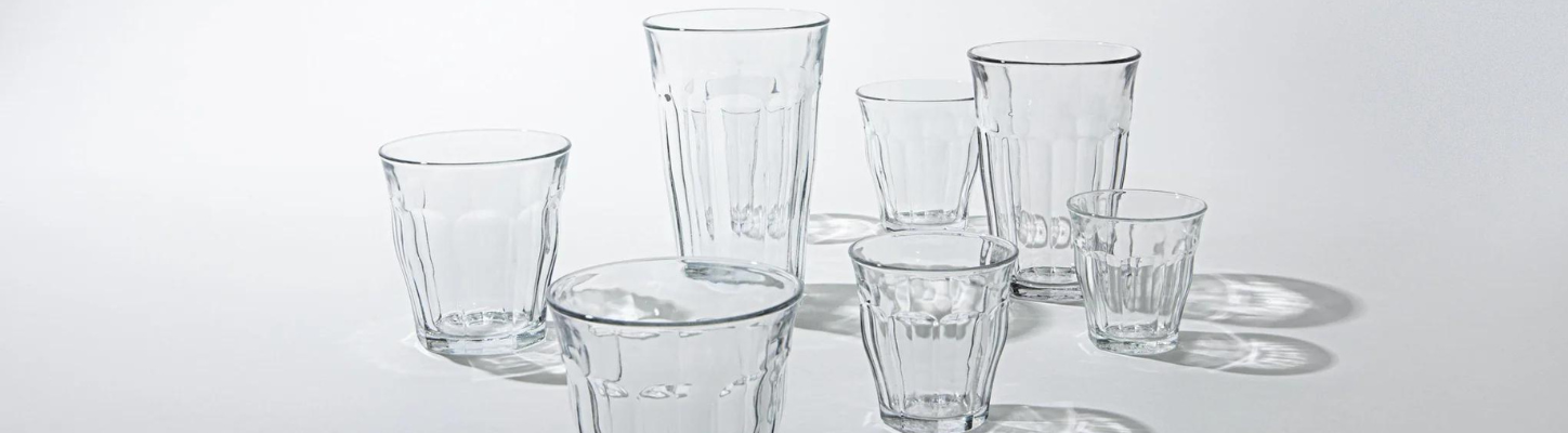 Samling av tomme glass i ulike størrelser på en hvit bakgrunn.